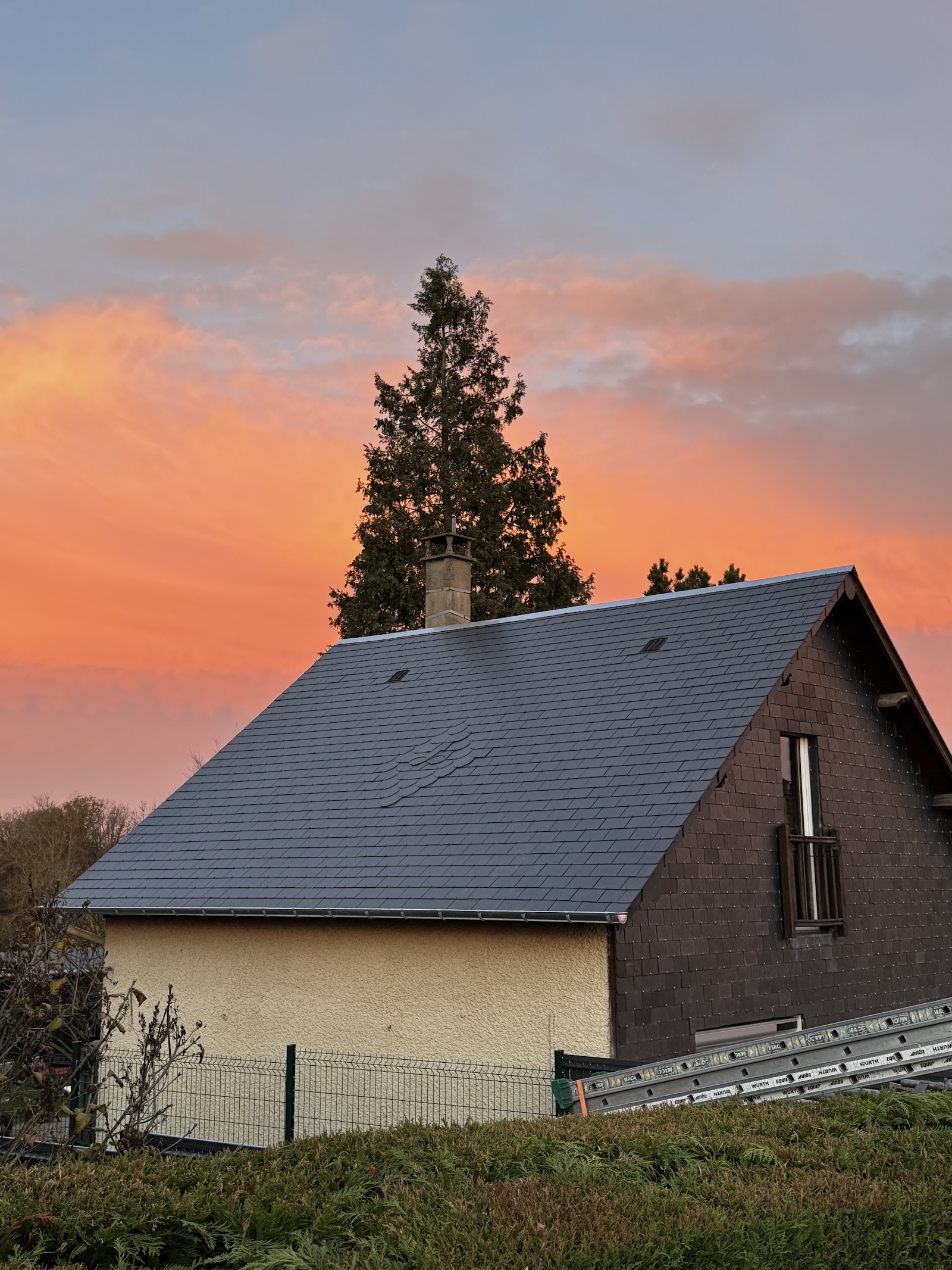 Toiture en ardoise avec motif floral sous un ciel de coucher de soleil