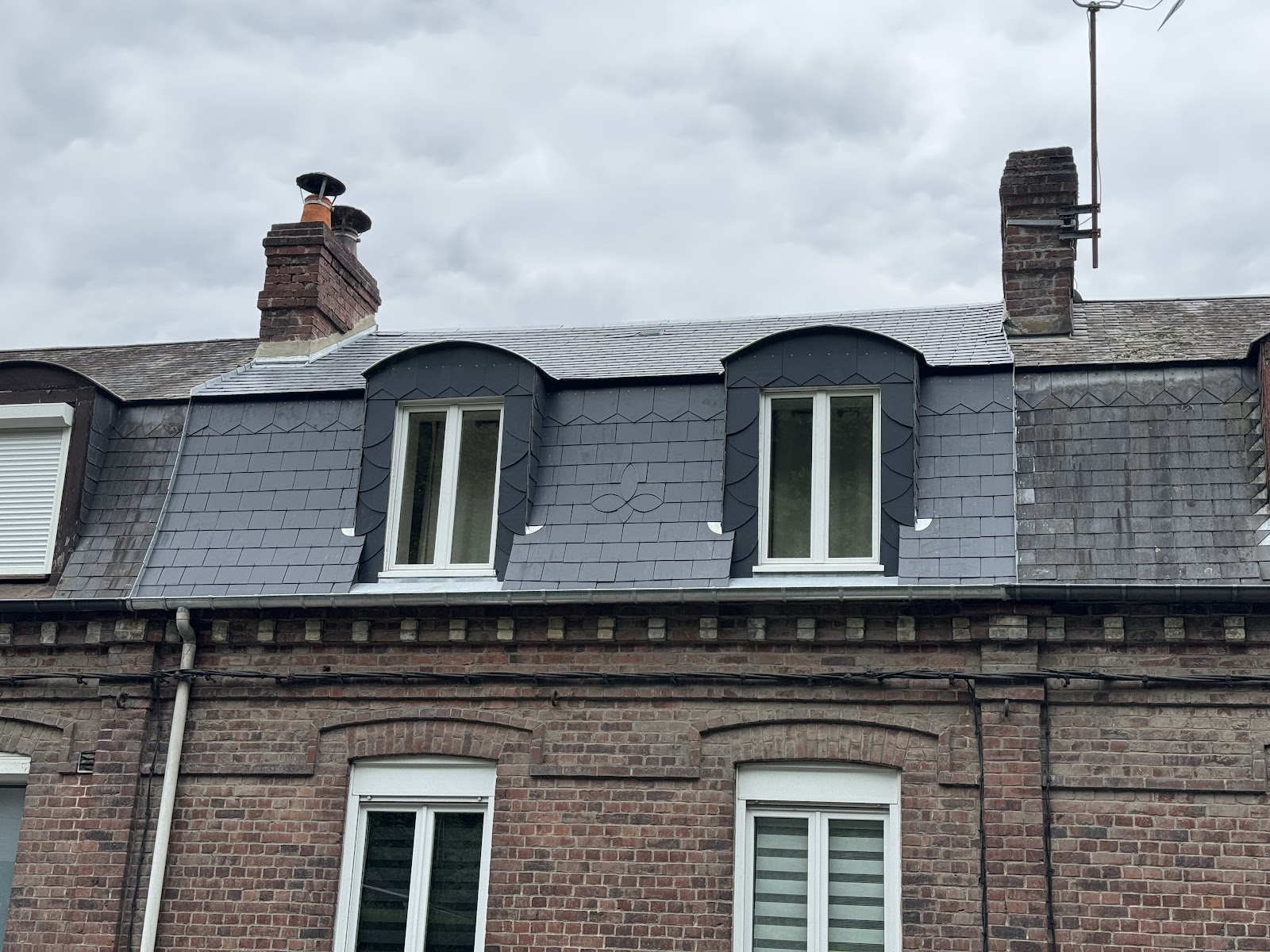 Détails de lucarnes en ardoise sur façade en brique
